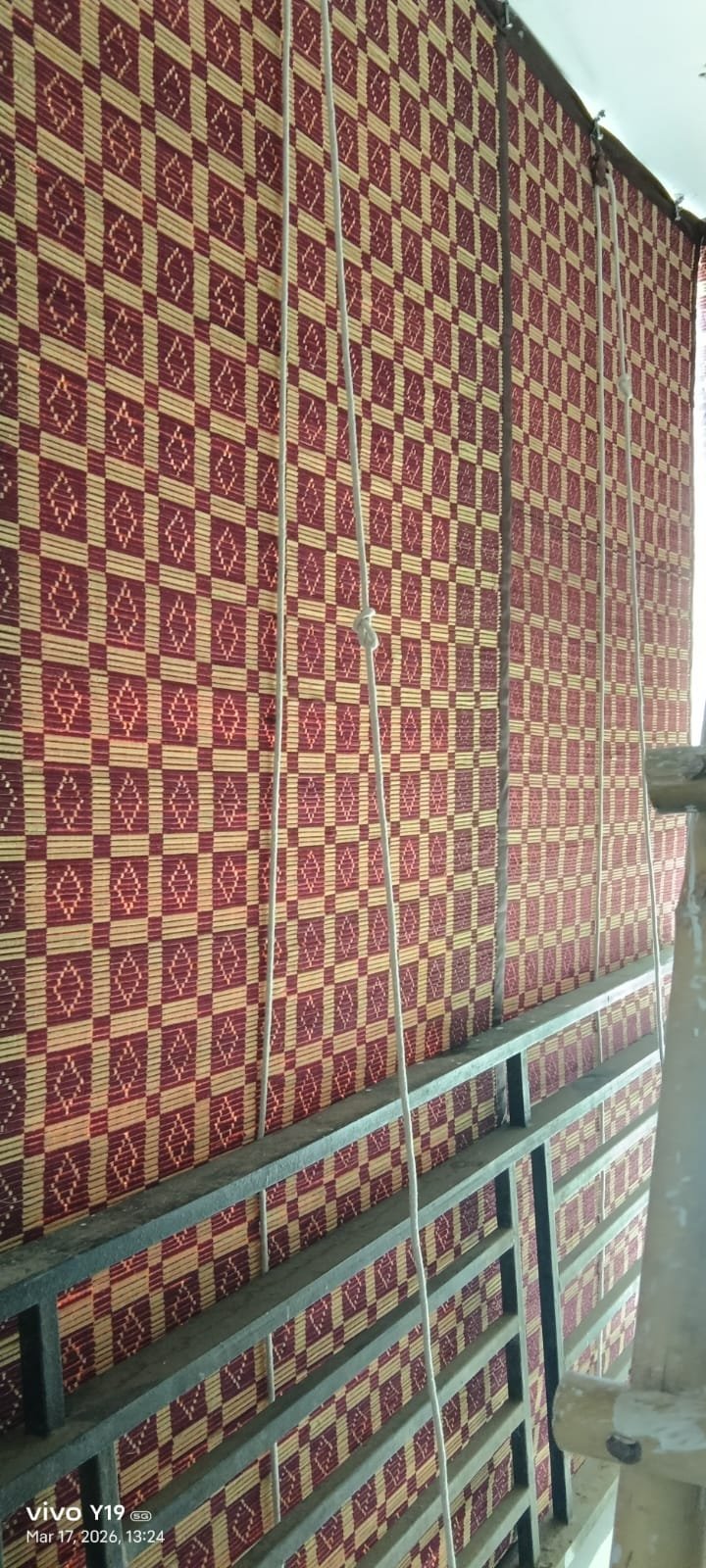 Artisan red and cream patterned chick blind along apartment balcony railing